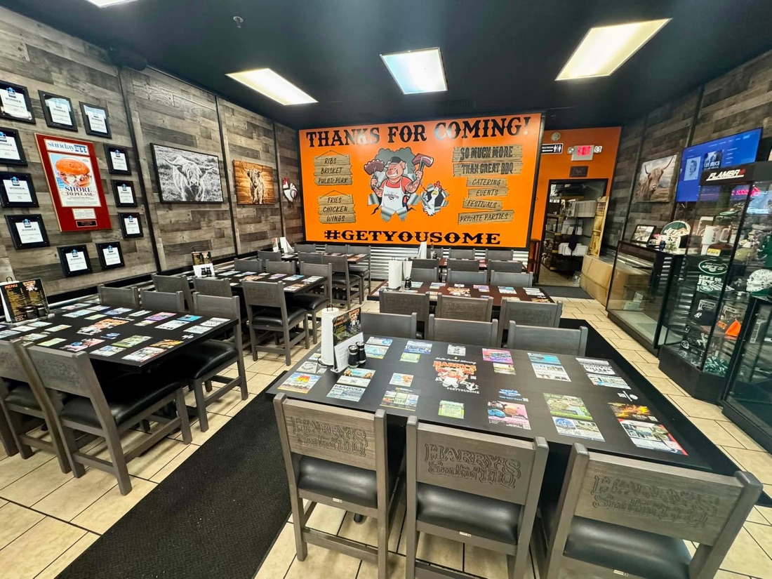 The dining room at Harry's Smokin' BBQ, every table printed with the same set of local ads