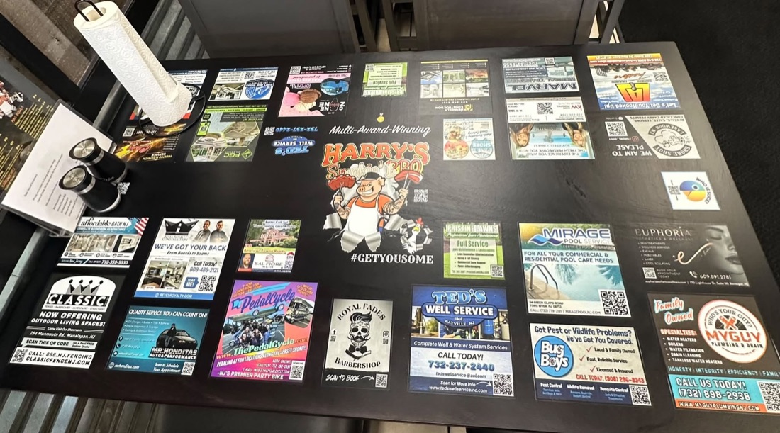 A finished table at Harry's Smokin' BBQ with the restaurant's logo in the middle and local sponsor ads around it