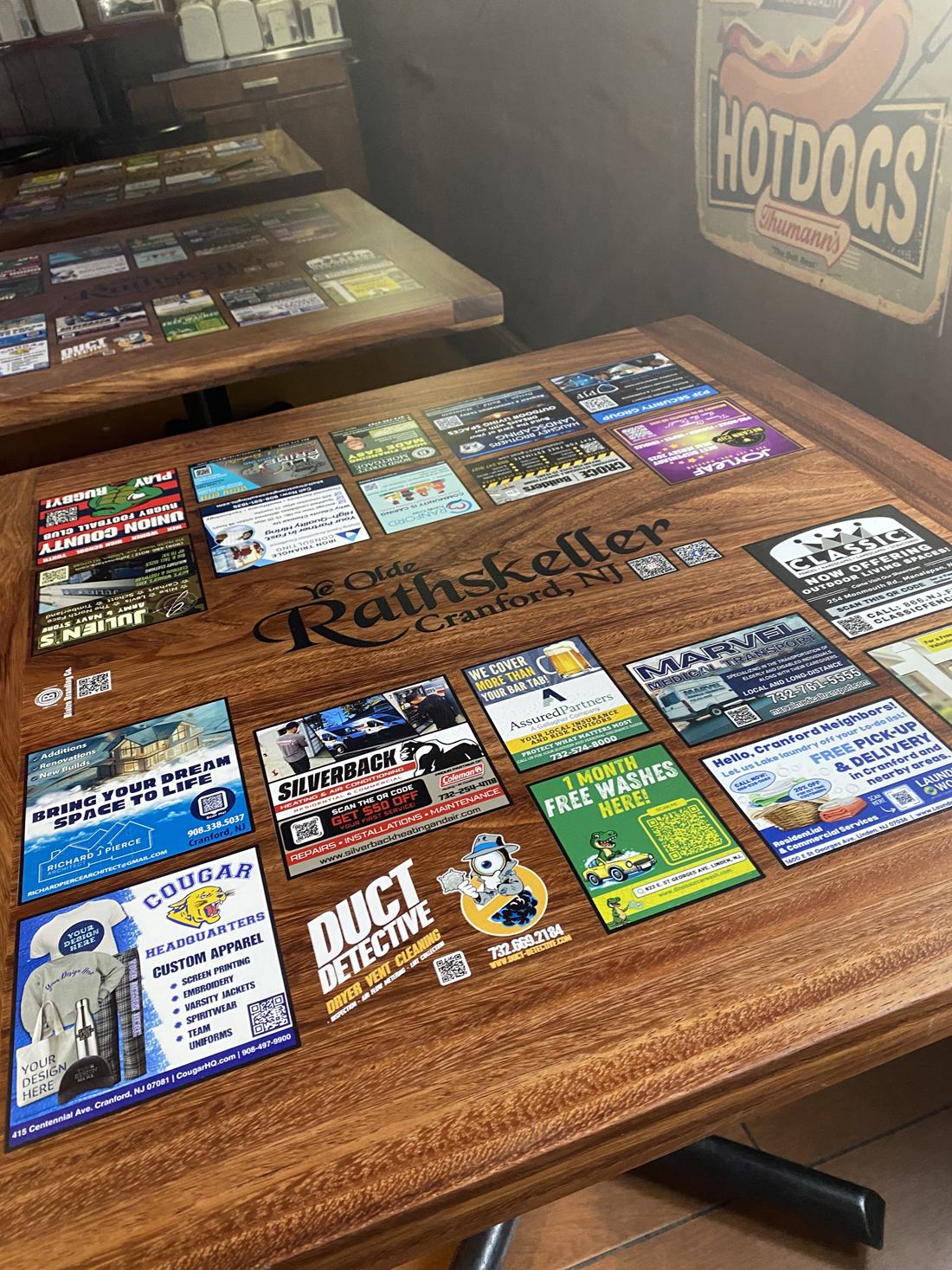 Hardwood tables at Ye Olde Rathskeller with sponsor ads around the restaurant's name