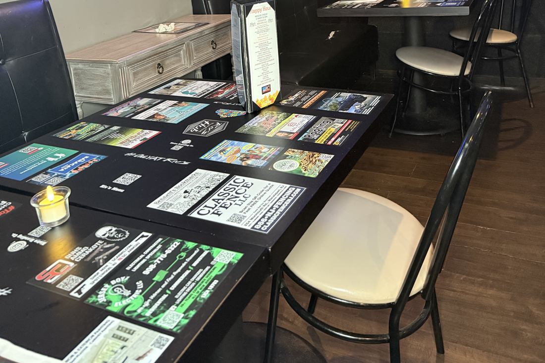 Black-finish tables at Riv's Toms River Hub carrying local ads